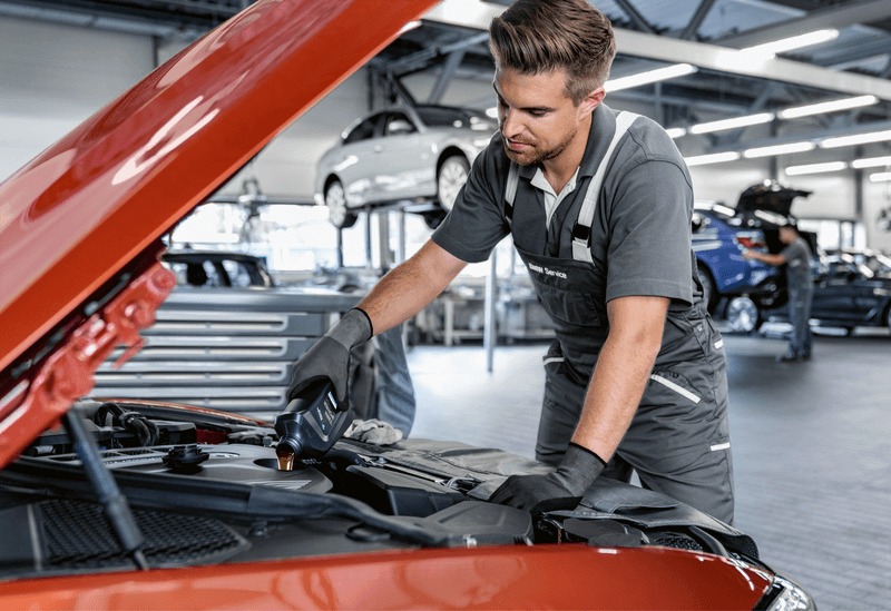 Technician adding engine oil during a workshop service