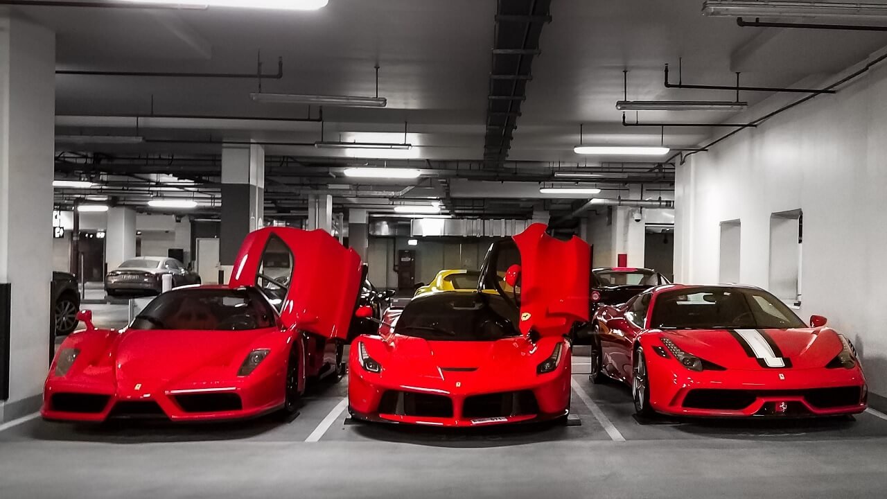 Three red Ferrari sports cars parked in an indoor garage