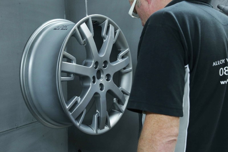 Technician checking Maserati alloy wheel damage before repair