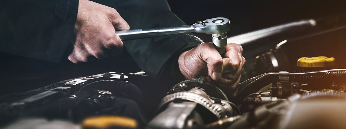 Technician checking replacement parts beside a luxury SUV in Dubai