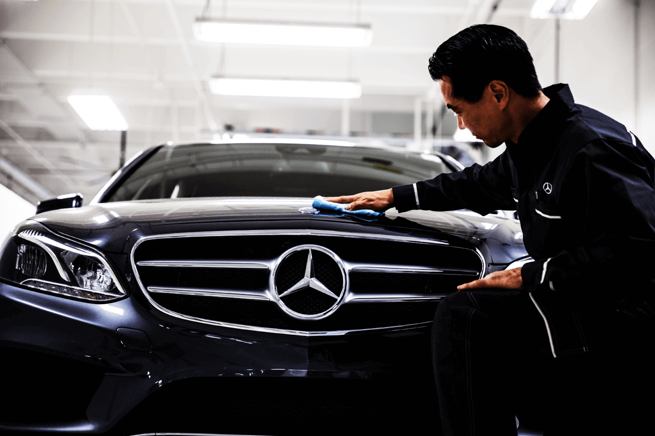 Dark blue Mercedes vehicle inspected by a technician in a workshop
