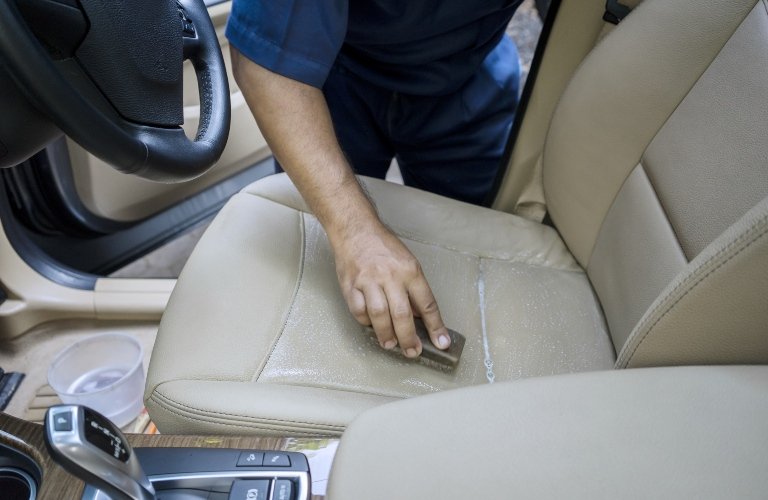 Technician inspecting and cleaning luxury leather seat upholstery