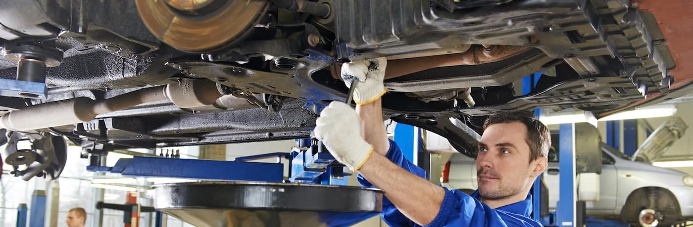 Technician inspecting suspension components beneath a raised vehicle