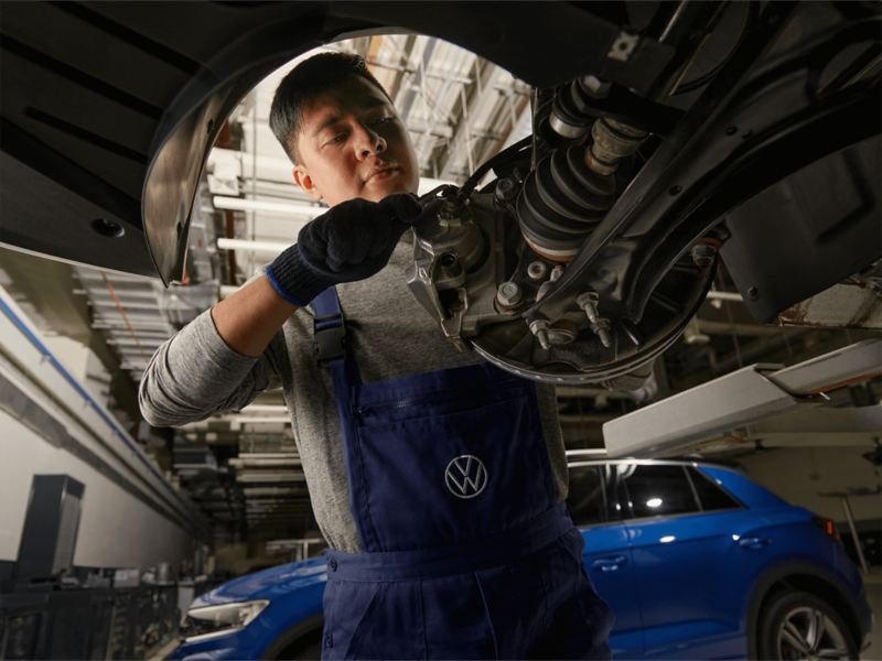 Technician inspecting a Volkswagen brake assembly in a workshop