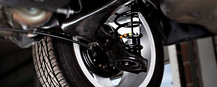 Technician inspecting GMC suspension components and ride height