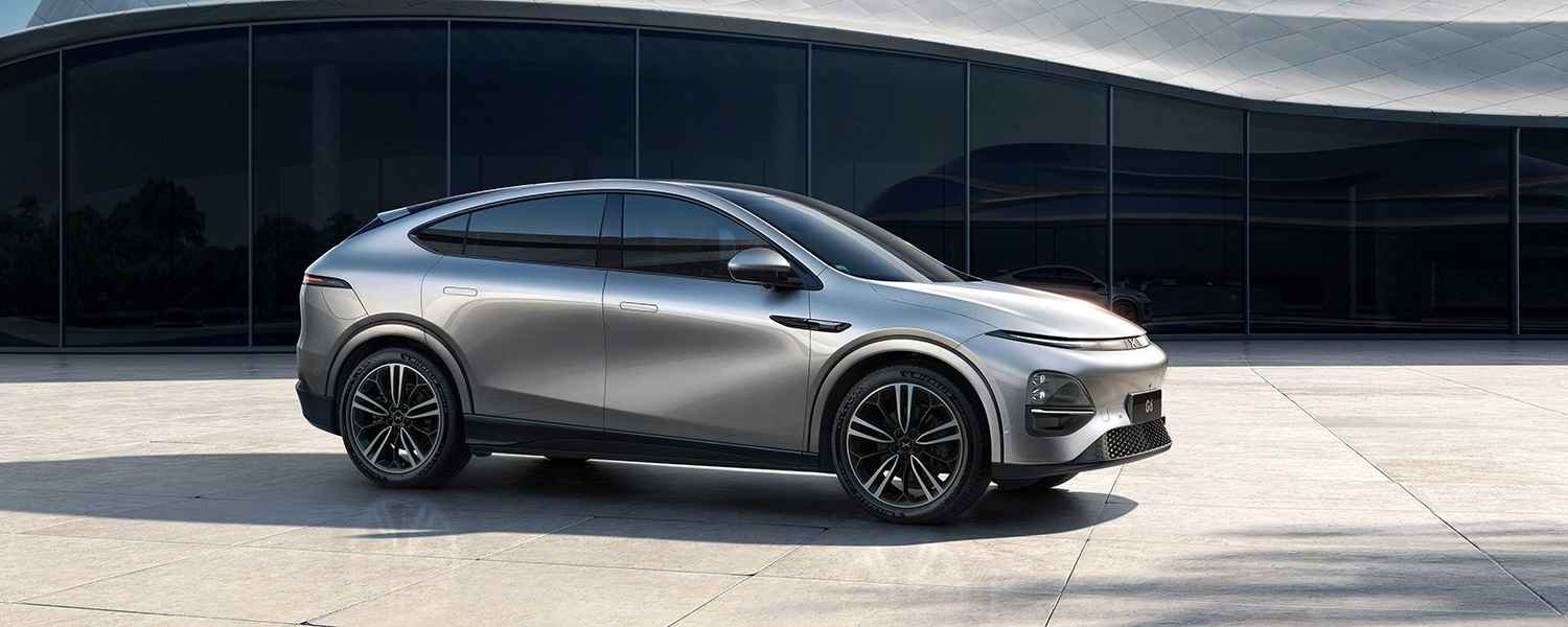 Silver XPeng electric SUV parked outside a glass-fronted building