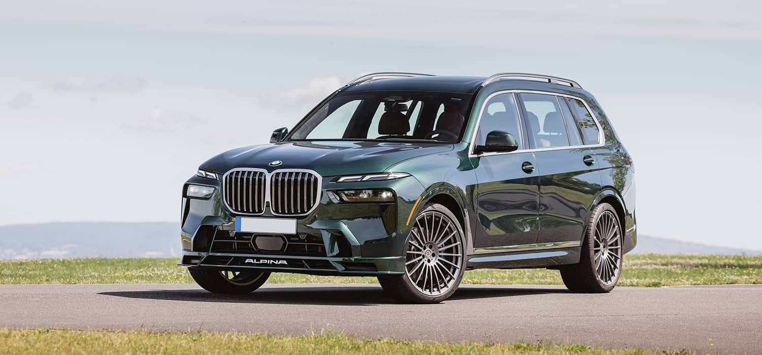 Green Alpina SUV parked beside a grass verge