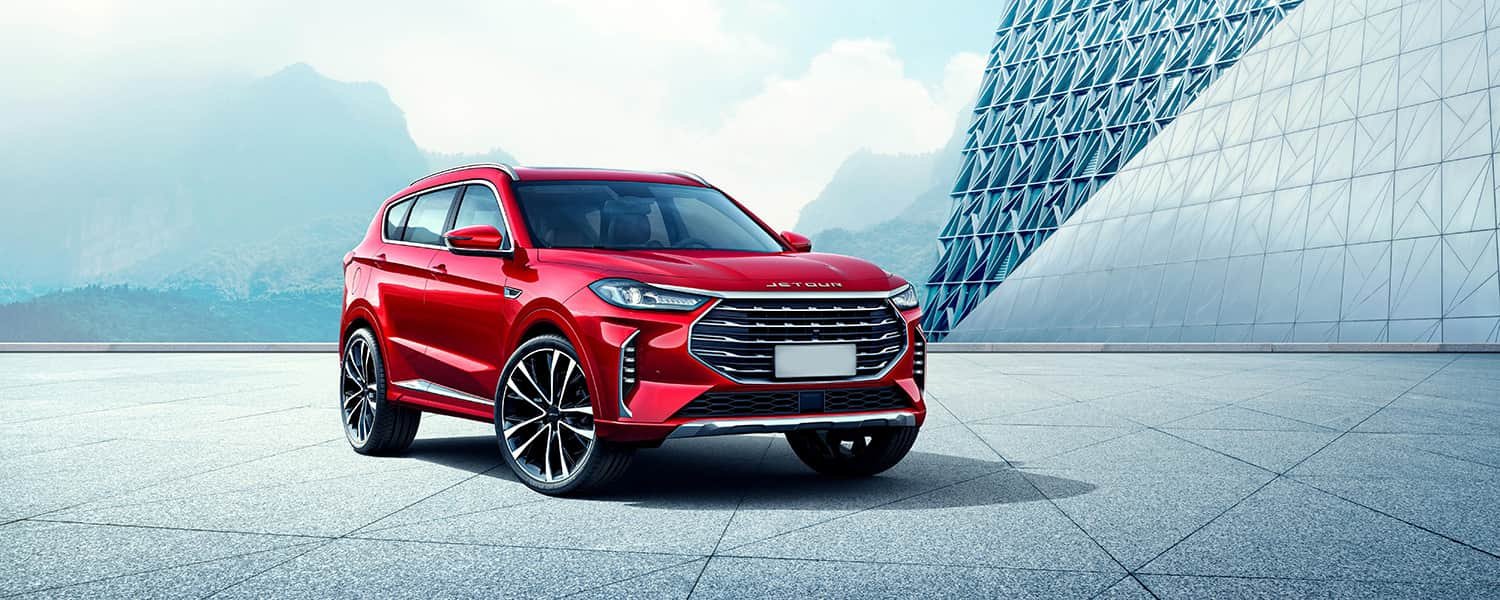 Red Jetour SUV parked beside a modern building