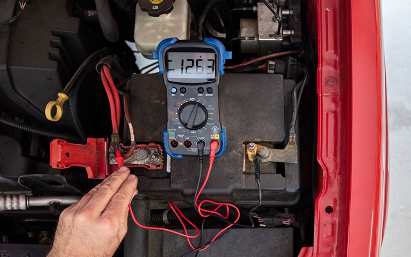 Technician using a tester during a car battery inspection