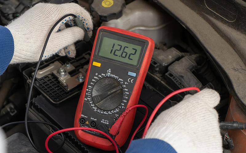 Technician measuring battery voltage during an electrical test