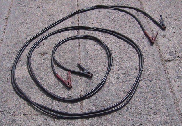 Disconnected jumper cables with red and black clamps laid out for inspection