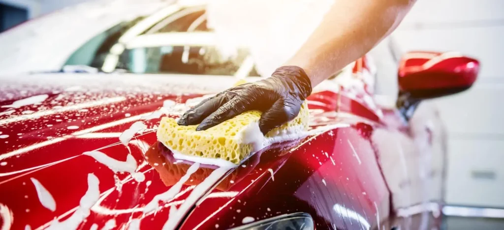 Technician washing the exterior of a car in Dubai