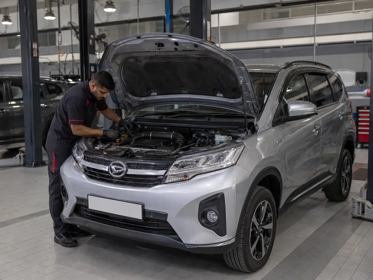Technician inspecting engine and cooling components on a current Daihatsu Terios in a workshop