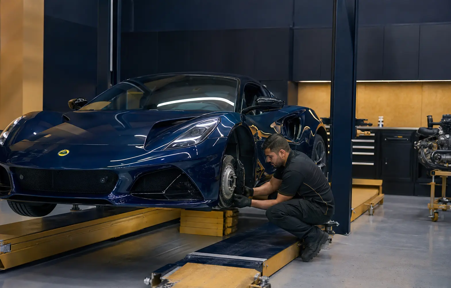 Technician inspecting Lotus Emira brakes and suspension on a low-rise lift