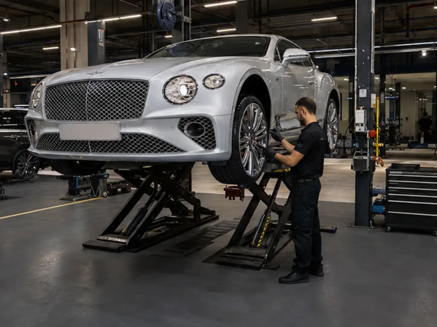Technician inspecting brakes tyres and suspension on a modern Bentley Continental GT
