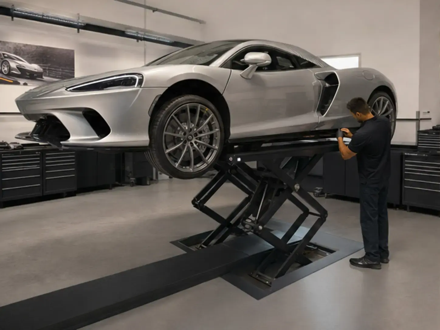 Technician inspecting brakes tyres and suspension on a McLaren GT using a suitable low-clearance lift