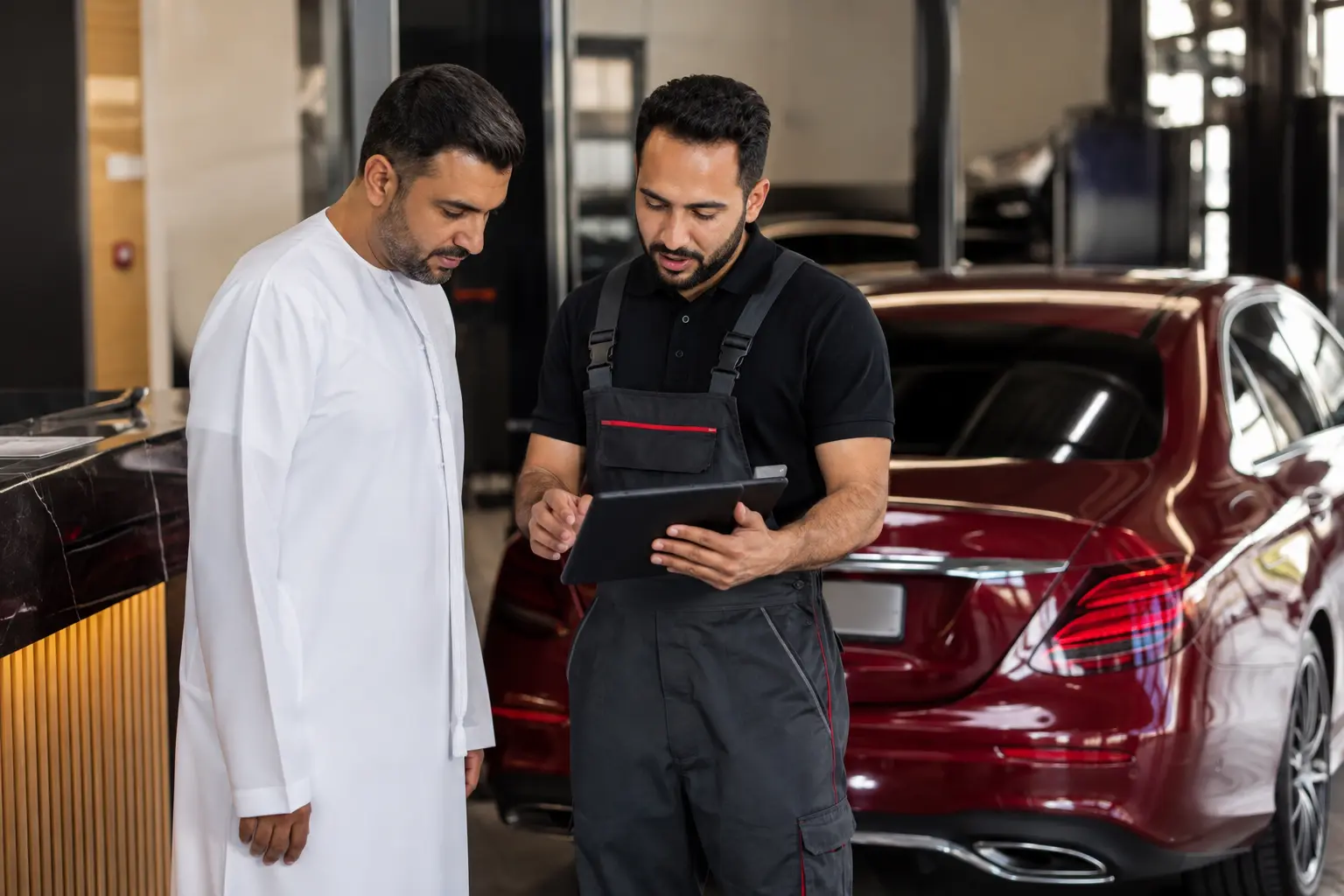 Technician explaining completed Mercedes battery test findings to a vehicle owner