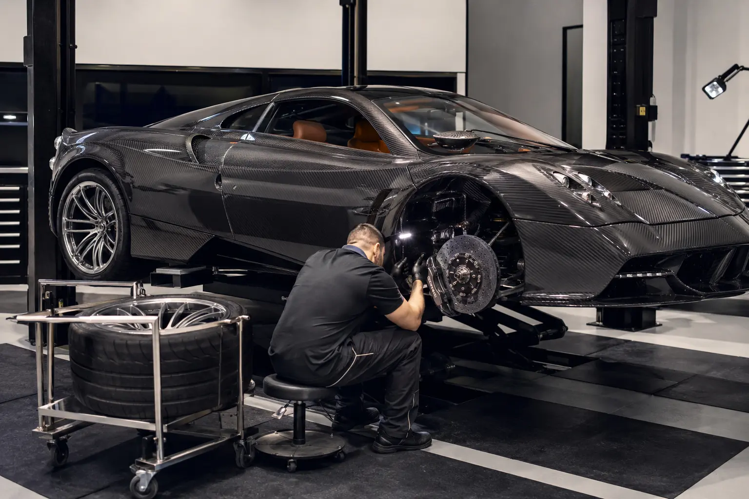 Technician inspecting Pagani brakes and suspension with the wheel removed