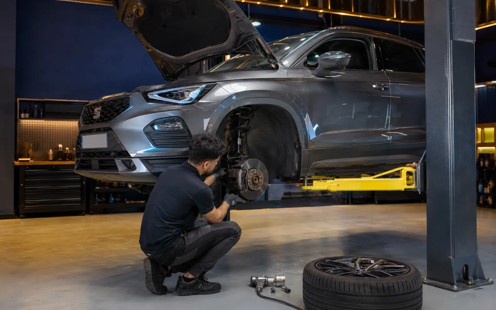 Technician inspecting the front brake and suspension of a current SEAT Ateca