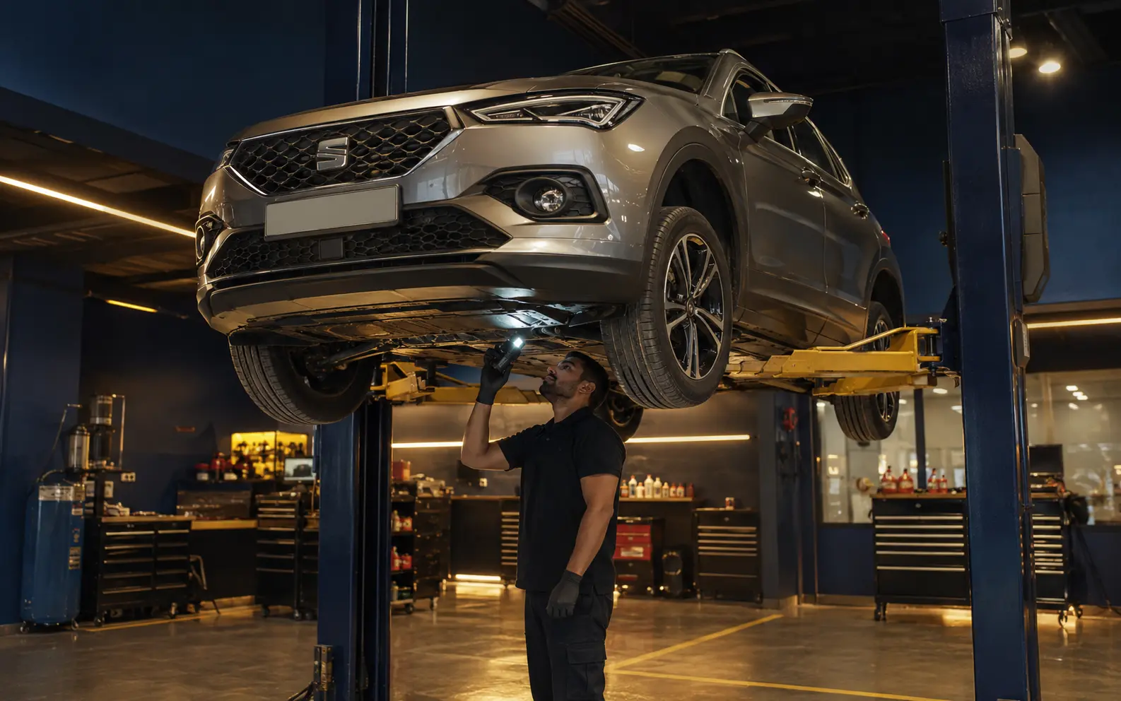 Technician inspecting the transmission area and underbody of a current SEAT Ateca
