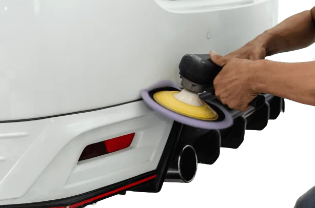 Machine polishing the painted rear panel of a white car